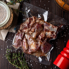 Raw marinated meat in a vacuum packaging on a dark wooden table, food delivery