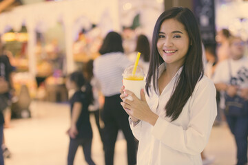 Beautiful Asian woman drinking juice in shopping mall