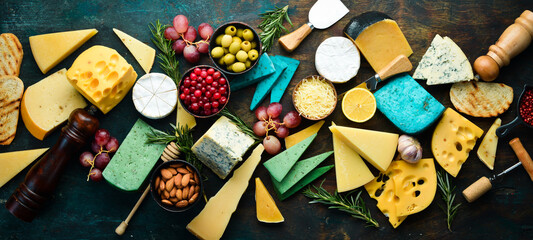 Big set of cheese, nuts, grapes and snacks on a black stone background. Free copy space. Top view.