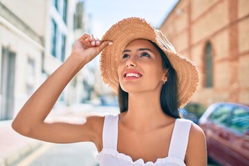 Young latin girl wearing summer style and smiling happy at street of city.