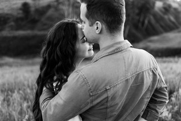 Beautiful young woman and a man walk, hug and kiss in nature at sunset.