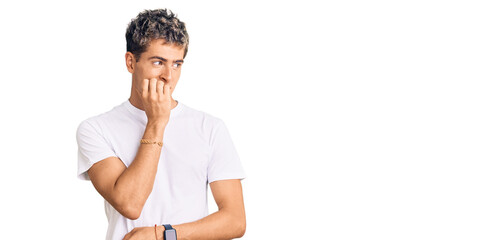 Young handsome man wearing casual white tshirt looking stressed and nervous with hands on mouth...