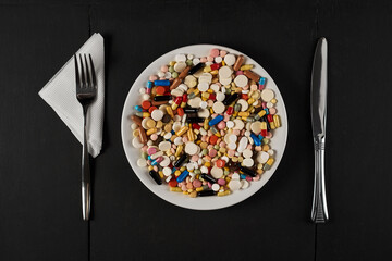 a large number of colored tablets and capsules on a plate.