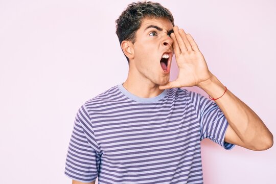 Young handsome man wearing casual clothes shouting and screaming loud to side with hand on mouth. communication concept.