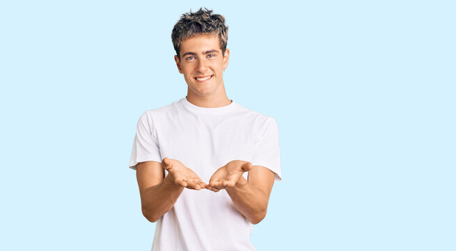 Young handsome man wearing casual white tshirt smiling with hands palms together receiving or giving gesture. hold and protection
