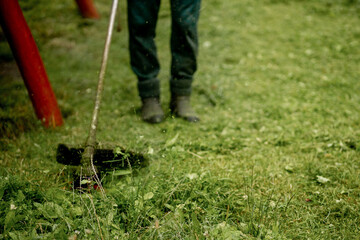 The head of a gasoline manual lawnmower while working against the background of freshly mown grass.