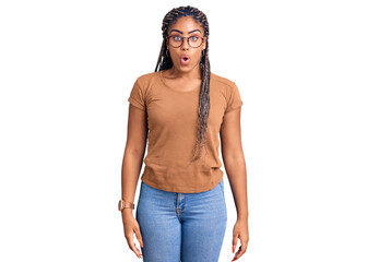 Young african american woman with braids wearing casual clothes and glasses scared and amazed with...