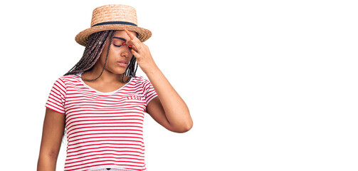 Obraz na płótnie Canvas Young african american woman with braids wearing summer hat tired rubbing nose and eyes feeling fatigue and headache. stress and frustration concept.