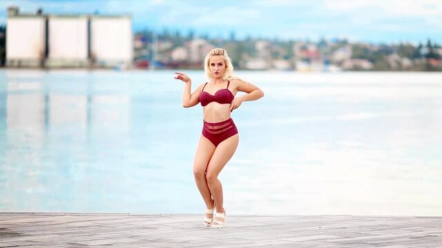 Sexy young blonde woman model dance in bikini on pier