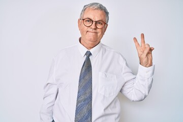 Senior grey-haired man wearing business clothes smiling with happy face winking at the camera doing victory sign. number two.