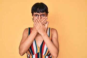 Beautiful brunettte woman wearing casual clothes and glasses shocked covering mouth with hands for...