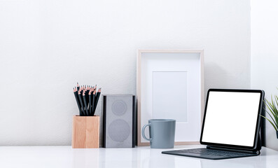 Mockup creative workspace with blank screen tablet and magic keyboard on white table.