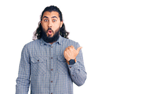 Young arab man wearing casual clothes surprised pointing with hand finger to the side, open mouth amazed expression.