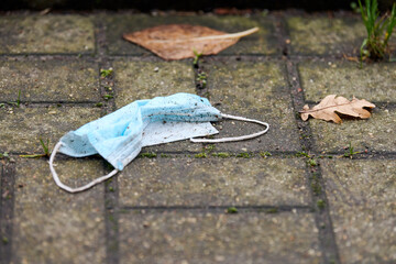 Used medical mask on street ground