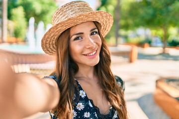 Young hispanic woman on vacation smiling happy making selfie by the camera at the park.