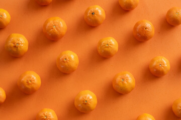 (Selective focus) Flat lay, close-up view of some tangerines arranged symmetrically on an orange background. Fresh fruits, concept of healthy food.