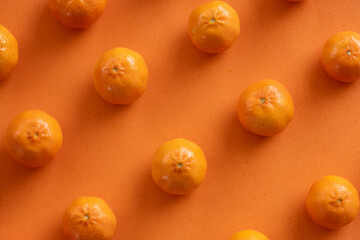 (Selective focus) Flat lay, close-up view of some tangerines arranged symmetrically on an orange background. Fresh fruits, concept of healthy food.