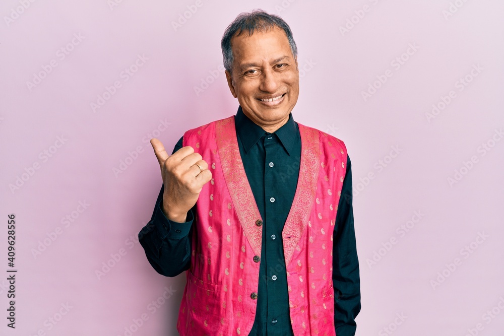 Poster middle age indian man wearing traditional indian clothes smiling with happy face looking and pointin