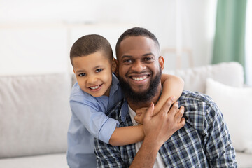 Portrait Of Cheerful African Father And Son Hugging At Home