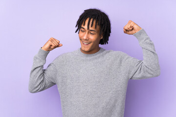 Young african american man isolated on purple background celebrating a victory