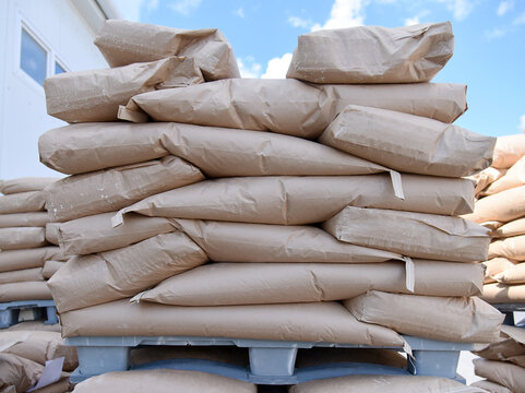 Bags of flour and dry powder in the warehouse, in the open air, are stacked on pallets.Factory for processing and sorting.