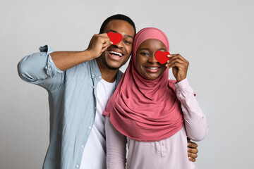 Playful black lovers covering one eye with red hearts