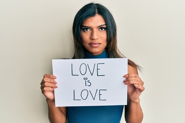 Fototapeta na wymiar Young latin transsexual transgender woman holding paper with love is love message skeptic and nervous, frowning upset because of problem. negative person.
