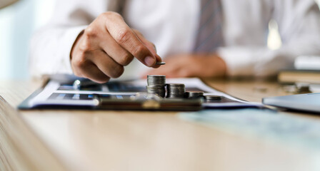 A businessman is putting the coins in order to keep them neatly, he will invest his savings for growth, the idea of saving money to grow.