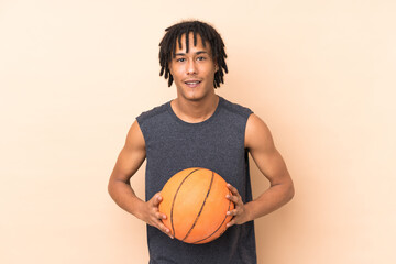 Young african american man isolated on beige background playing basketball