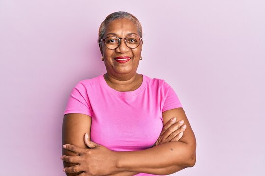Senior african american woman wearing casual clothes and glasses happy face smiling with crossed arms looking at the camera. positive person.