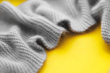 Blurred Gray knitted scarf asymmetrical frame  on yellow .  Symbolize warmth, love and tenderness.  Valentine's Day concept. Trendy Color 2021. Copy space