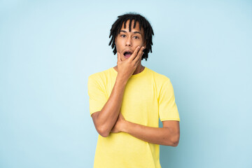 Young african american man isolated on blue background surprised and shocked while looking right