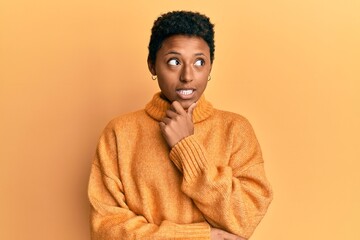 Fototapeta premium Young african american girl wearing casual clothes with hand on chin thinking about question, pensive expression. smiling with thoughtful face. doubt concept.