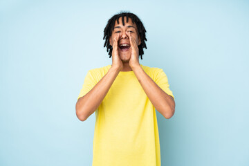 Young african american man isolated on blue background shouting and announcing something