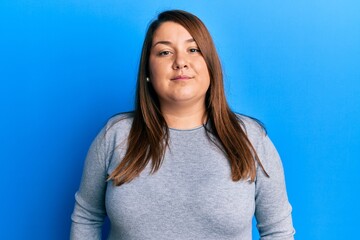Fototapeta premium Beautiful brunette plus size woman wearing casual clothes relaxed with serious expression on face. simple and natural looking at the camera.