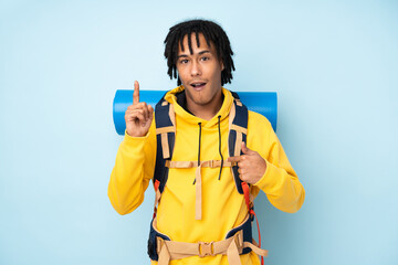 Young mountaineer african american man with a big backpack isolated on a blue background with...