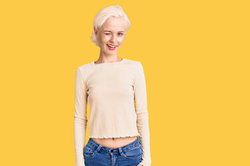 Young blonde woman wearing casual clothes winking looking at the camera with sexy expression,...