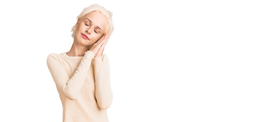 Young blonde woman wearing casual clothes sleeping tired dreaming and posing with hands together while smiling with closed eyes.