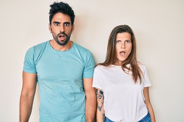 Beautiful young couple of boyfriend and girlfriend together in shock face, looking skeptical and sarcastic, surprised with open mouth