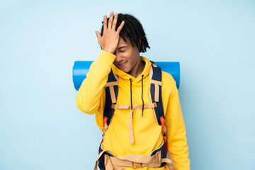 Young mountaineer african american man with a big backpack isolated on a blue background having...