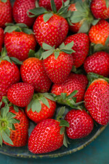 Ripe strawberries in a plate close-up on a blue-green background