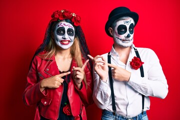 Couple wearing day of the dead costume over red pointing aside worried and nervous with both hands, concerned and surprised expression