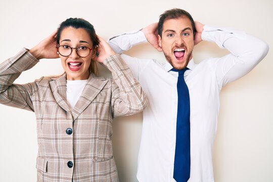 Beautiful couple wearing business clothes crazy and scared with hands on head, afraid and surprised of shock with open mouth