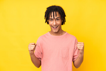 Young african american man isolated on yellow background celebrating a victory in winner position