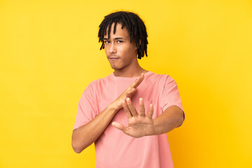 Young african american man isolated on yellow background nervous stretching hands to the front
