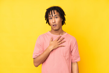 Young african american man isolated on yellow background surprised and shocked while looking right