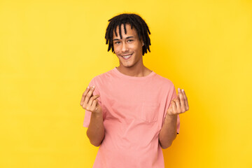 Young african american man isolated on yellow background making money gesture