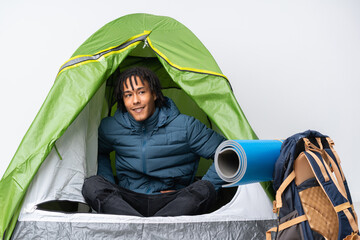 Young african american man inside a camping green tent posing with arms at hip and smiling