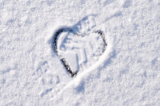 Symbol of end of love, giving up on love. Downtrodden heart shape on snow surface
