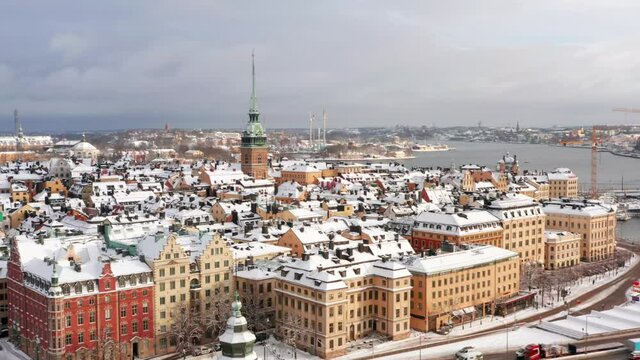 Winter stockholm city old town rooftop view. White snow covered old buildings downtown aerial drone clip. Church and towers from above in cold Sweden